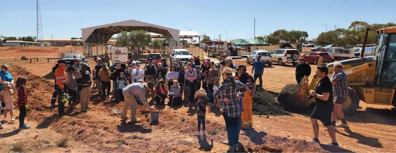 Residents gather around a planting demonstration beside the Coober Pedy playground.